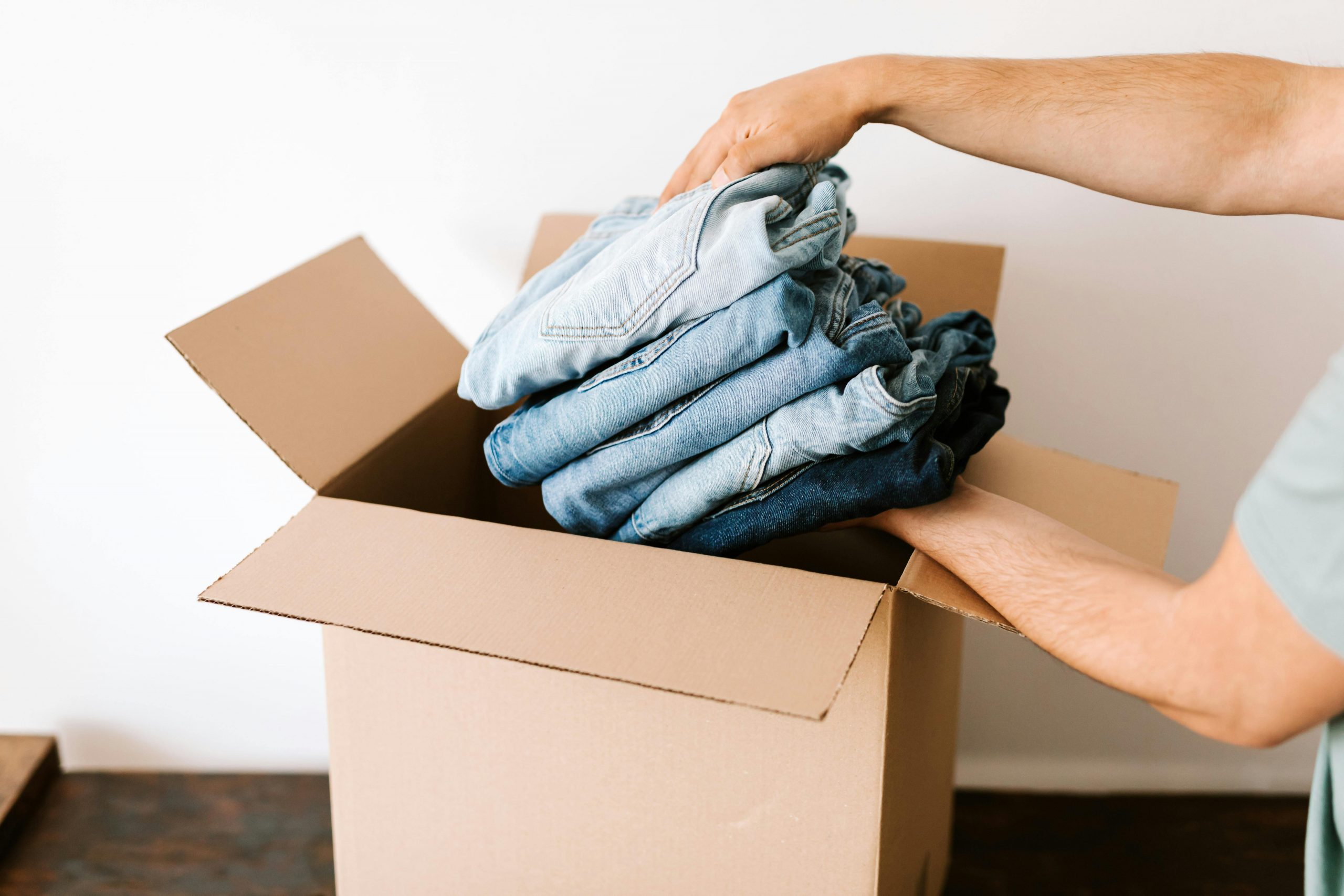 man packing jeans into a moving box